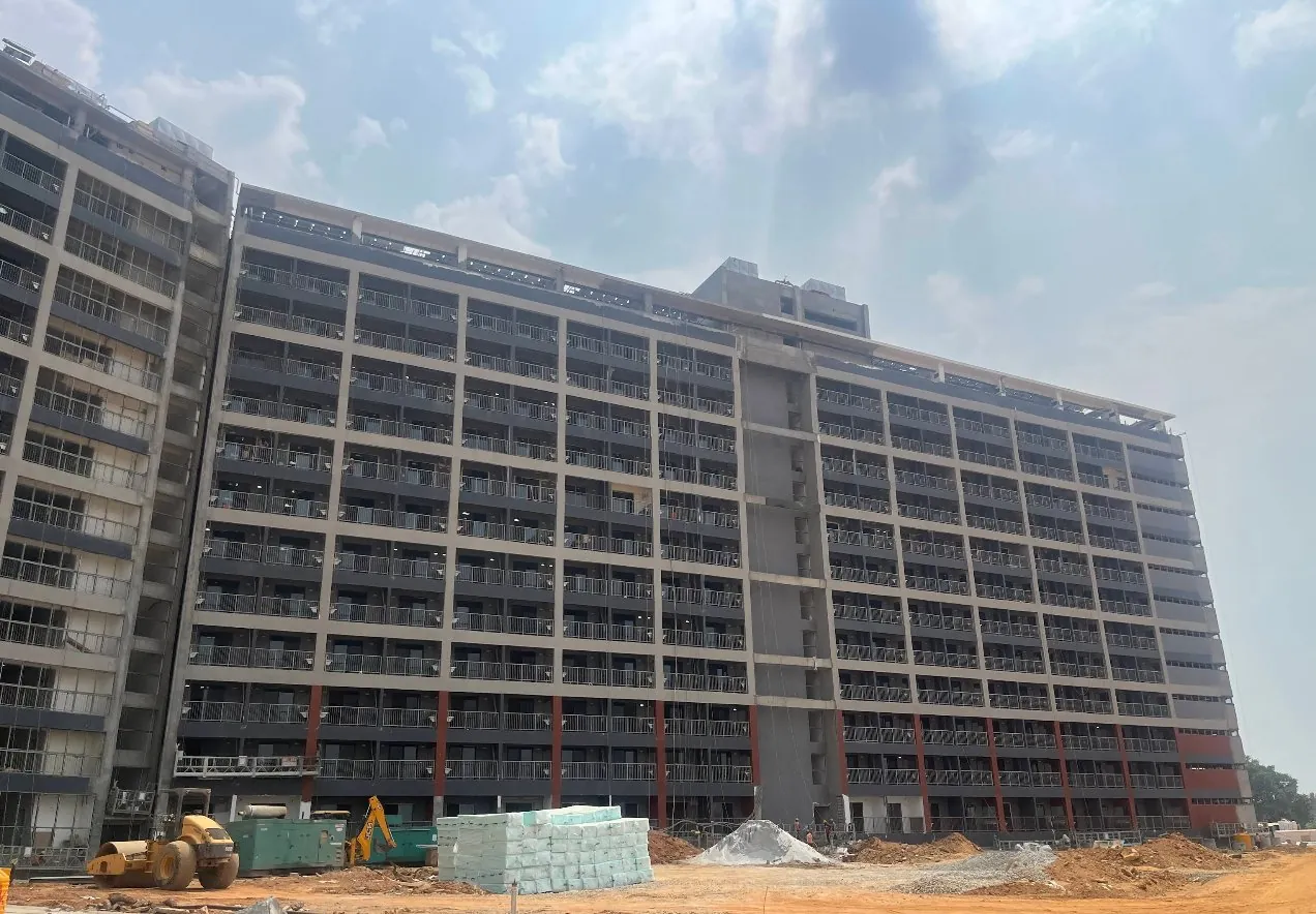 Foxconn Project Elephant, Bengaluru: the D-series building's facade nearing completion, with cement bags and site machinery in the foreground
